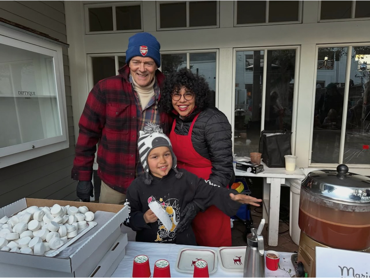 Malena and Clive smiling together with their child at a chocolate event.